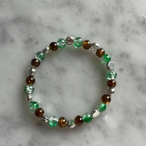 Armband - Snyggt armband med spräckliga glaspärlor i brun och grön med silvriga detaljer💫💫