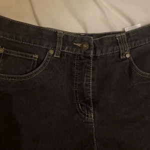 Lågmidjade mörka jeans  - Snygga lågmidjade jeans med ljusa sömmar och coola detaljer. Byxorna är i mycket bra skick och säljs för att de ej passar mig längre. De passar för någon 167-180cm lång och en s/m i storleken. Skriv ifall ni vill ha mer information ;)