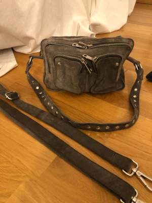 Äkta Núnoo väska  - Äkta Núnoo väska som säljs pågrund av att den inte kommer till användning. Den är mycket rymlig och den är klädd i grå mocka, den har även silvriga detaljer. Köptes för 1399kr! (Pris kan diskuteras!☺️)