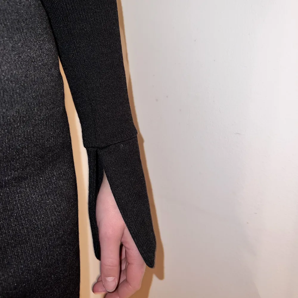 En svart långärmad klänning i lite stickat material med en urringning med ”krage” från Gina Tricot, långa ärmar med slits . Klänningar.