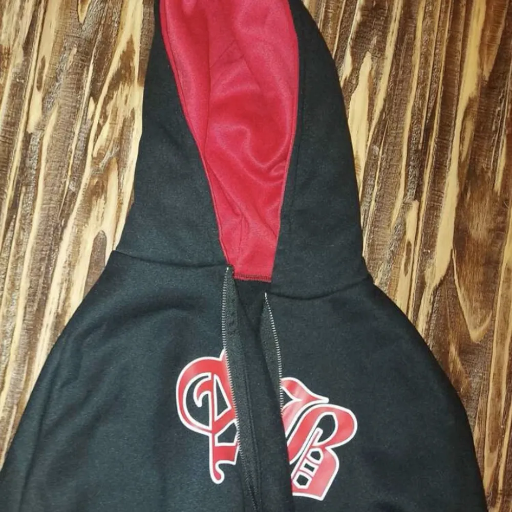 En hoodie med dragkedja med röd luva och lite text fram  Flis inuti och mjuk  Säljer pågrund av för liten för mig. Hoodies.
