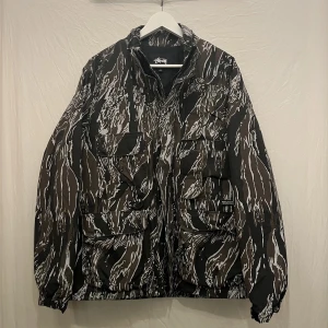 Stüssy Jacka - Jacka i camouflage från Stüssy. Fint skick. Passar till regn. 