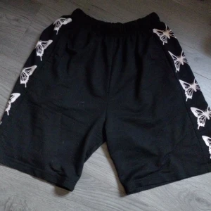 Shorts  - Bekväma shorts. Dem har ett snyggt print med fjärilar och är svarta som passar till det mesta. Den är i storlek L. Har resår i midjan så dem sitter åt men lösa i benen.