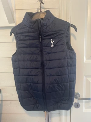 Tottenham väst  - Säljer sonens Tottenham väst.  Uppskattar strl till small( 158)  En reva på baksidan, men kan enkelt tråcklas / sys ihop. Har ej gjort det, men kan göra det om nån är intresserad. Köpt i London , i fan shoppen.  Nypris ca 600 