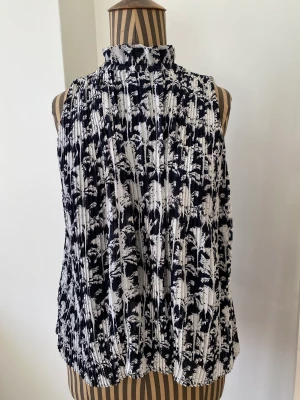 Härlig topp från Samsoe - Polotopp från Samsoe Samsoe. Använd en eller två gånger och i nyskick! Mönster med palmer och vit och mörkblå i färgen.