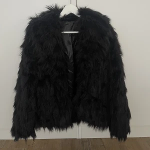 Svart pälsjacka - Fake päls. Köpt second hand. Passar XS-M beroende på hur man vill att den ska sitta. Stor och fluffig i modellen.