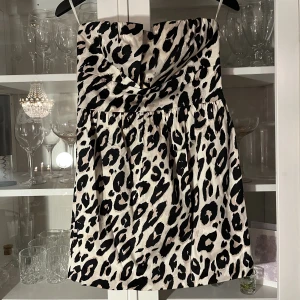 Klänning - Kortkort klänning i leopardmönster. Matchas snyggt med en svart kavaj, ett måste i varje garderob! Diskret dragkedja i ryggen. Strl 34, använd men bra skick. 