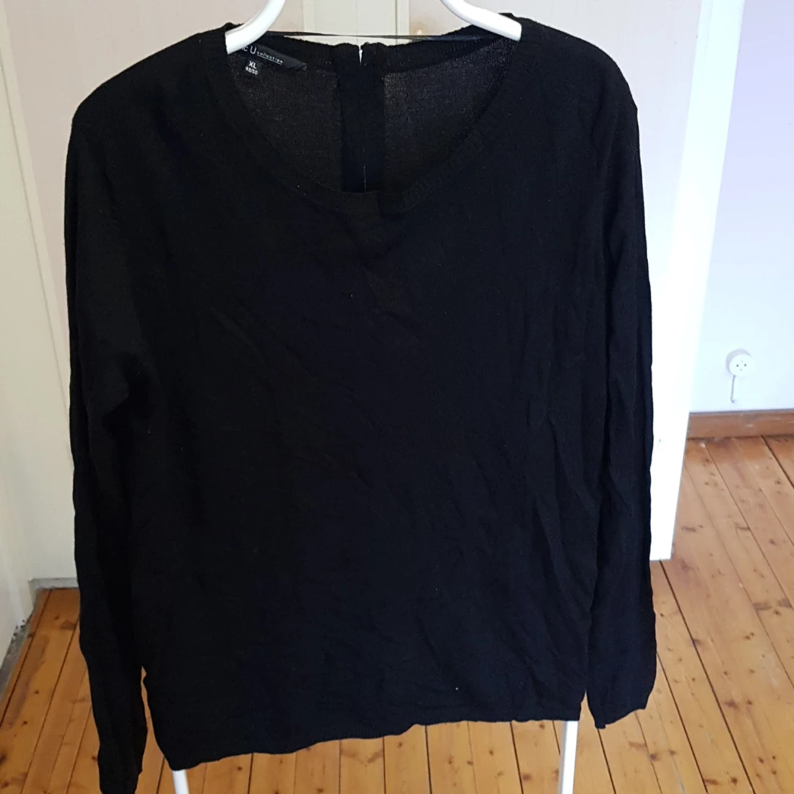 Långärmad tröja med dragkedja bak i nacken.