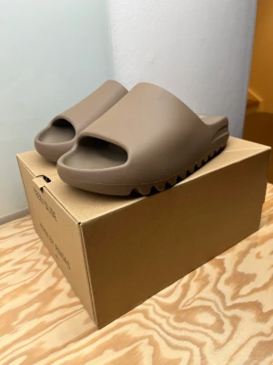 Yeezy slide Earth Brown  - Yeezy slide Earth Brown  Skick: 9,5/10 VNDSWT Storlek: US 9 Eu 43  Note: tofflorna är endast testade inomhus, är i nyskick!   
