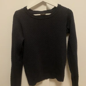 Bubbligt stickad långärmadtröja - Säljer en mörkblå stickad tröja från Vila med fint mönster. Storlek medium. Knappt använd. Material: 50% akryl 50% bomull.