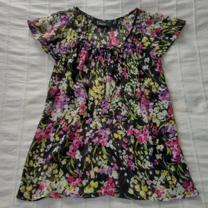 Färgglad/mönstrad y2k topp i mesh, storlek 36 - Mönstrad topp i meshliknande material. Flowy och lite genomskinlig. Snörning i halsen. Tyget har släppt lite vid kanten runt halsringningen. Om man tycker att det syns går det säkert att fixa med svart sytråd. Storlek 36.