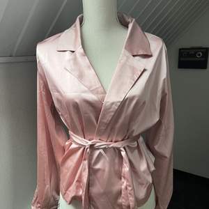 En rosa silkesskjorta med band som man knyter. Köpt från Bikbok i storlek M.