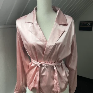 Silkesskjorta med band - En rosa silkesskjorta med band som man knyter. Köpt från Bikbok i storlek M.