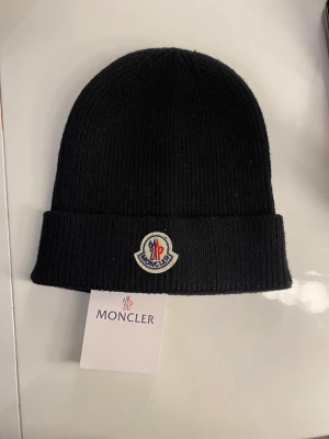 Moncler mössa  - Säljer min Moncler mössa som jag fick i julklapp, den är helt oanvänd. Säljer den för 1000kr. (Kvitto finns ej)