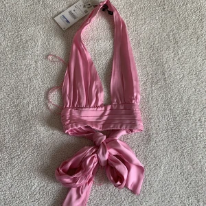 ZARA HALTERNECK TOPP - Superfin halterneck topp från ZARA. Har tyvärr aldrig kommit till användning, ny med tags kvar. Har dock hittat ett litet streck (bläckpenna?) på kanten, syns väldigt lite och går nog att få bort i tvätt. 🌻 Knyts med en stor fin rosett i ryggen. 💖