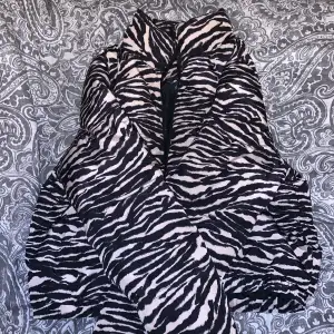 En tjock och varm dunjacka i bra skick med zebra mönster, zebra mönstret är i Beige svart.