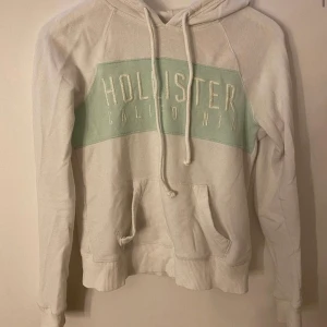 Hoodie Hollister - Vit hoodie med turkos text från hollister, fint skick, storlek XS