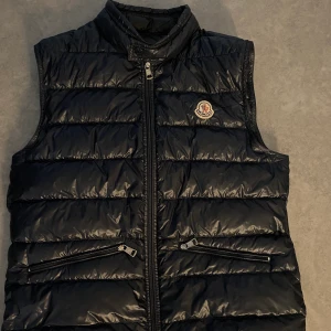 Moncler väst - Säljer min marinblåa moncler väst då den aldrig kommer till användning. Den är i storlek 1 som motsvarar S men passar även XS. Den är använd fåtal gånger då den inte riktigt passa mig.🤍