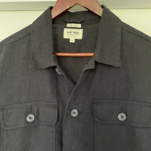 Linneskjorta  - Svart linneovershirt/skjorta från East West, köpt på brohters. Stl M. Köpare står för frakt! Skriv för för fler bilder.