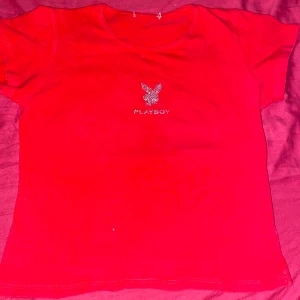 röd playboy tshirt med rhinestones - tyvär har den ingen lapp men den e ungefär 38-40 i storleken.   den e så fin men tyvär är det inte min stil längre:(  skriv om du vill ha exakt mått o sånt:))