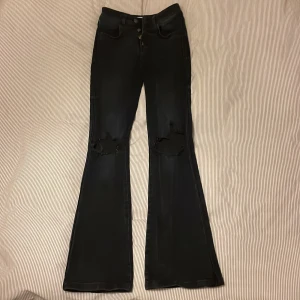 Svarta bootcut jeans❤️‍🔥❤️‍🔥 - Svarta bootcut jeans med hål på knäna, säljer pga lite för små och kommer ej till användning, storlek xs och jeansen är från Elsa Ekmans kollektion från bikbok, använd endast fåtal gånger, frakt tillkommer alternativt möts upp i Sthlm❤️‍🔥❤️‍🔥