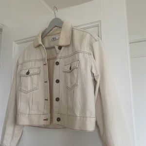 Jacka - Tunn jacka i beige från zara. Använd 1-2 gånger. Jättefin med tjocktröja under eller till våren!! Den är i kortare modell med knappar i brunt.