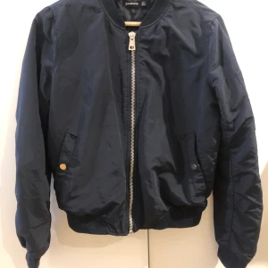 Bomberjacka - En marinblå bomberjacka med tre fickor (en på ärmen) i gott skick. Inga anmärkningar! 