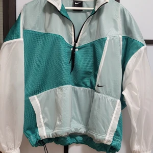 Nike Sportswear Tech Pack Women's Jacket - Sportjacka från Nike, mycket bekväm och lämplig för sportaktiviteter, jackan kombinerar mesh och ett genomskinligt vävt tyg för att lägga till subtila variationer av färg och textur till denna lätta och energiska jacka.  Oversize passform eller rymlig pas