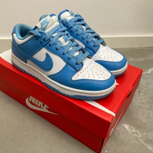 Nike Dunk University blue - Nike Dunk University Blue. Använda men i bra skick. Skorna är i originalbox och kommer med crease-skydd.