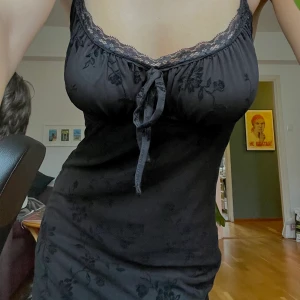  Klänning - Svart klänning från Urban Outfitters med en svart underklänning och över är ett tunt, genomskinligt spetsmateral med ett diskret blommönster. Superfin! Den är använd 1 gång tidigare. (Sista bilden är tagen vid mitten på smalbenen)