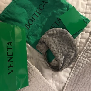 Bottega veneta väska - Så fin bottega väska ( mini jodie ). Den är i grå mocha och i använt skick men går nog att rena upp lite hos en skomakare. Inköpt på bottega butiken i Stockholm och har även ett kvitto. Nypris 21600kr! Kom med rimliga prisförslag! Jag byter tyvärr inte.