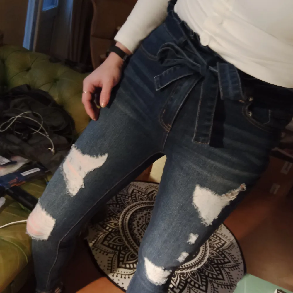 Mörkblå jeans med paperbagmidja och slitningar. Bältet i samma tyg går att ta av, och jeansen är snygga både med och utan det! Storlek S men mycket stretch. De är nästan nya. Verkligen fina och bekväma! 🖤. Jeans & Byxor.