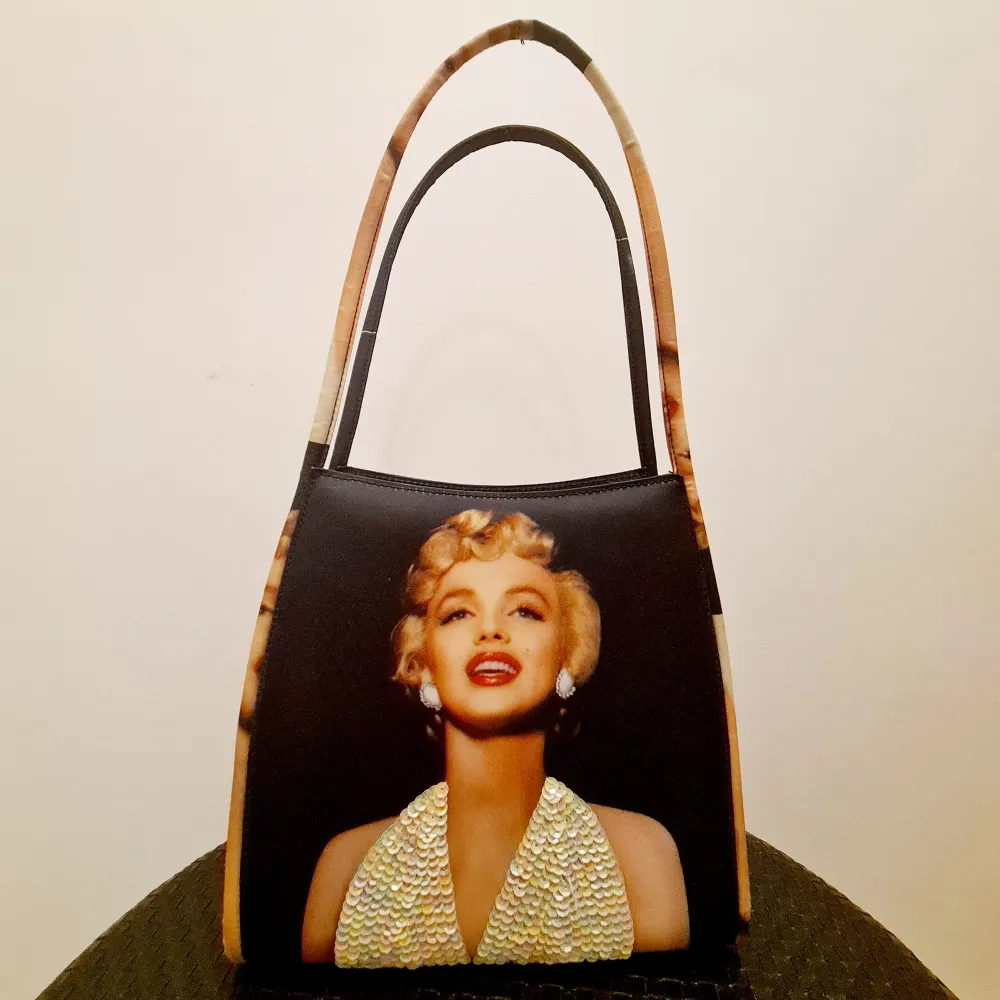 Handväska med Marilyn Monroe tryck. Oanvänd i nyskick som har stått i garderoben för länge. Väntar på ny ägare som vill använda den. <25×40cm. Väskor.