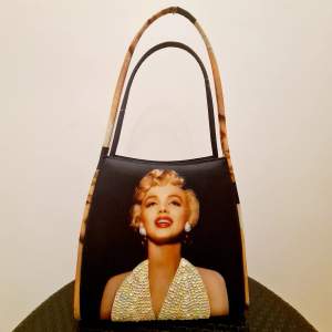 Handväska med Marilyn Monroe tryck. Oanvänd i nyskick som har stått i garderoben för länge. Väntar på ny ägare som vill använda den. <25×40cm