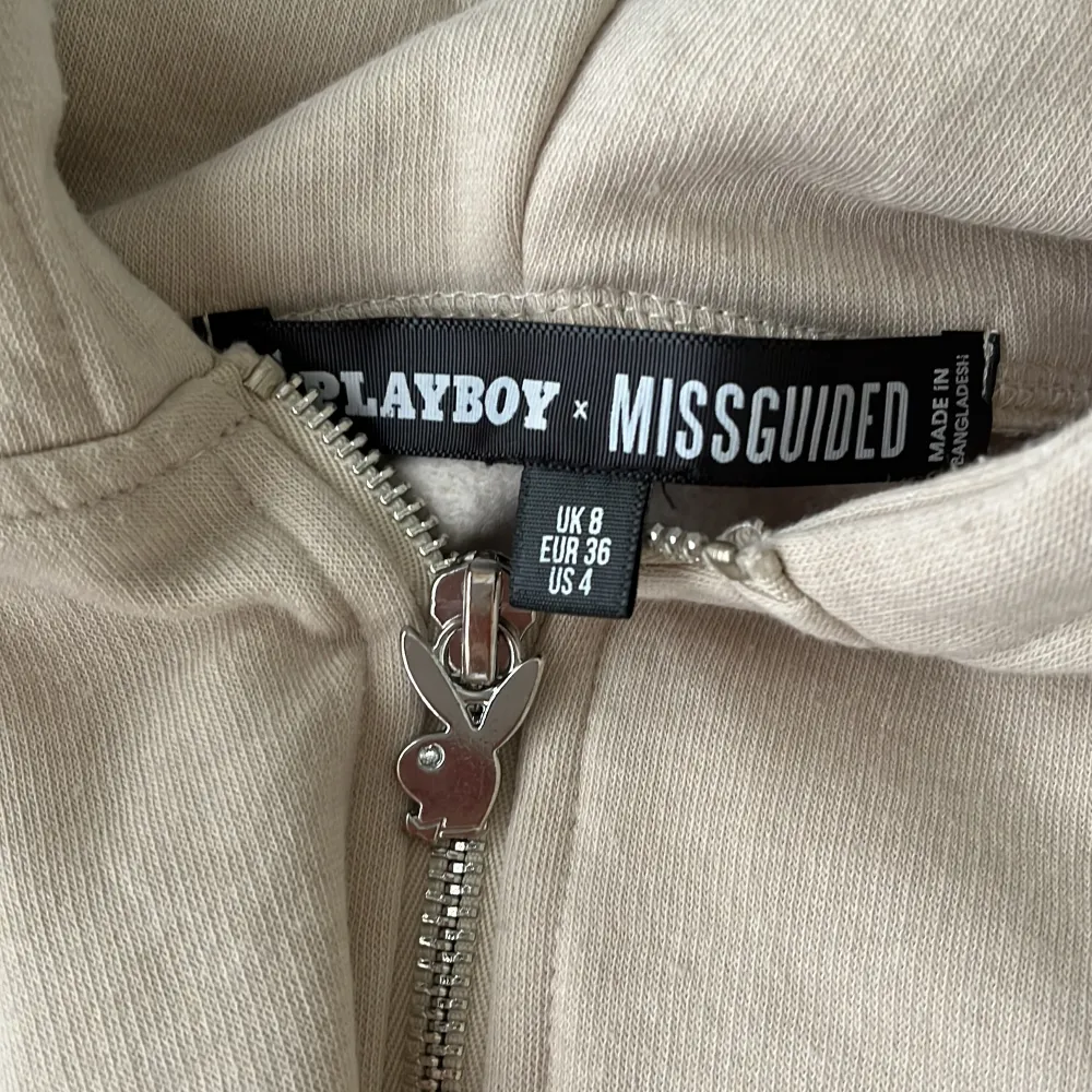 En beige hoodie med dragkedja i storlek 36 från märket Missguided x Playboy. Köpt på missguided men finns inte kvar på hemsidan längre. Tröjan är använd några gånger men är i mycket bra skick⭐️ Köparen står för frakten, jag tar endast betalt med swish!. Hoodies.