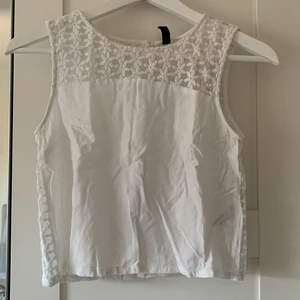 Vitt linne med ”öppen rygg” - Vitt linne från HM i storek 34. Den är genomskinlig över allt där det är blommor 