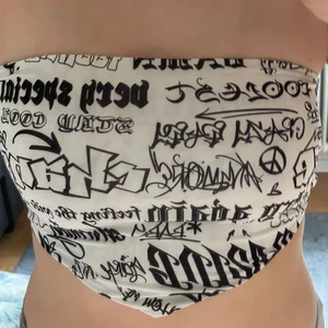 en magtröja med tryck - Vit margtröja med text utan axelband, baksidan har tre stycken snören.