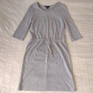 Oanvänd grå klänning med knytband, XS - Grå melerad klänning med knytband i midjan. Oanvänd men tvättad. 65% viskos 30% polyester 5% elastan. Storlek XS. 