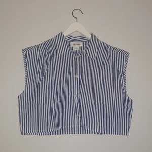 Monki Cropped Ärmlös Topp - Blå och vit-randig ärmlös cropped topp från monki. Skjortliknande väst med knappar.