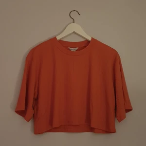 Monki Orange Cropped T-shirt - Orange cropped T-shirt från Monki. Ribbat tyg. Helt oanvänd och i storlek medium.