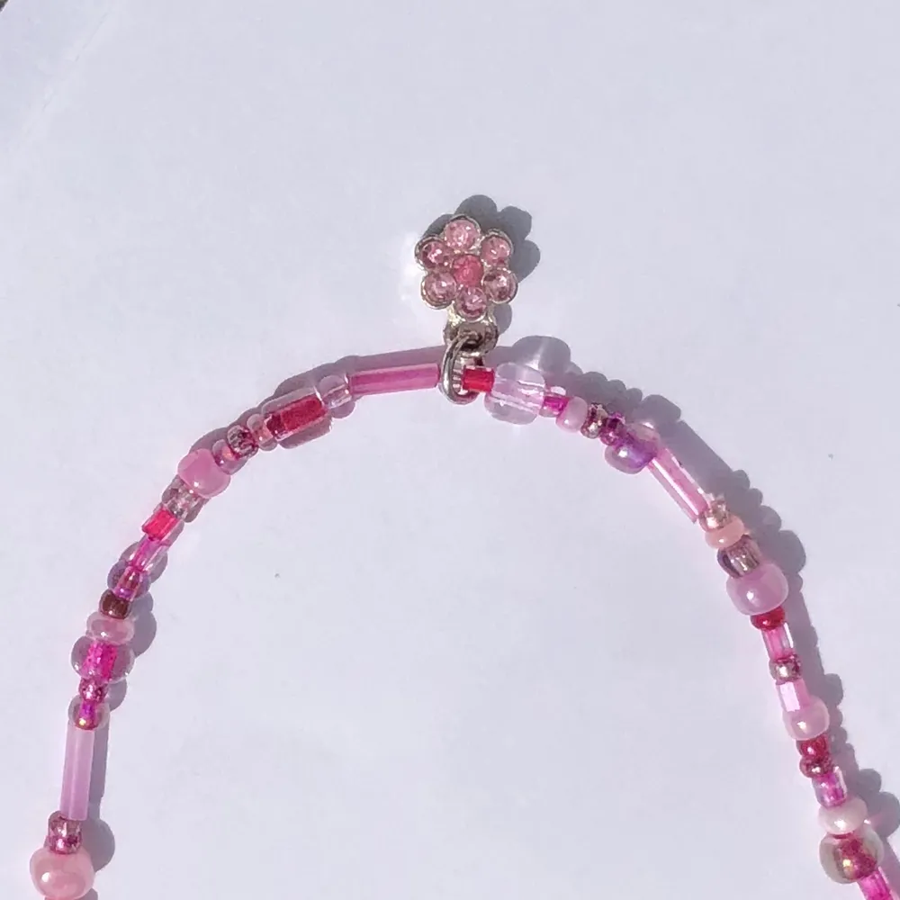 Ett rosa pärlhalsband med hänge i form av en blomma! 90:- . Accessoarer.