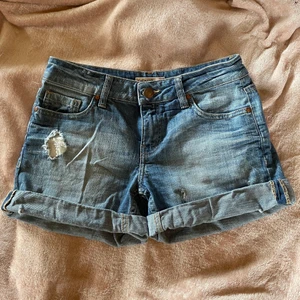 Blåa jeans shorts  - Ett par blåa jeans shorts med ett antal hål (menade att vara där) och slitningar. Flitigt använda, fortfarande i fint skick. För fler bilder och/eller mått är det bara att komma privat. Priset är exklusive fraktkostnaden och jag samfraktar gärna :)