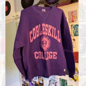 Sweatshirt  - En lila sweatshirt med ljusrosa tryck. Lite sliten men inte jättemycket. Storlek medium/large 