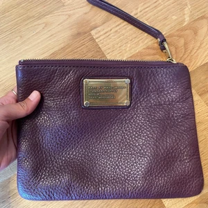Marc Jacobs clutchväska - Säljer den här fina väskan/clutchen i läder från Marc Jacobs. Färgen är mörklila/vinröd/aubergine. Den är i perfekt skick!  Mått: 21 x 6,5 cm