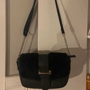 Fluffig axelremsväska silver - Säljer denna superfina fluffiga axelremsväskan (justerbar längd) med silverdetaljer 🖤 lite sliten på insidan vid knappen, men det går att laga och syns inte utifrån. Finns i DM för frågor / bilder