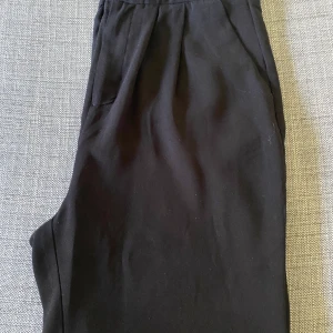Snygga midjehöga byxor strl M  - Svarta byxor med hög midja i polyester, strl M. Sköna och snygga byxor med lös passform längs benen, fullängd.   Kan skickas mot fraktkostnad. Djur- och rökfritt hem.  Kolla gärna mina andra annonser 😊