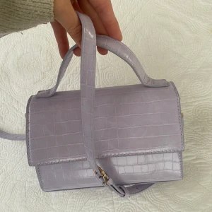 Lila handväska i ormskinnimitation - Så snygg väska från Åhlsens som aldrig blivit använd, så helt i nyskick. Nypris 599kr. 