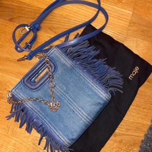 Maje väska - Säljer min maje väska i jeans tyg. Den är välanvänd men ganska unik då jag inte sett någon annan som har den. Kvitto medföljer och den köptes på NK 2021. 