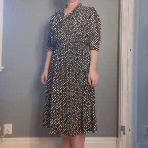 Prickig klänning  - Vintageklänning som har allt! Plisserad kjol, omlott i överdelen, tillhörande klätt bälte. 
