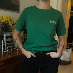 GANNI TSHIRT💚 - Säljer denna fina Ganni tshirten! Nypris ca 1000kr. Den har en fläck som syns på bilden, men den går förmodligen bort (inte försökt hårt) och säljs därför för 400 + frakt💚